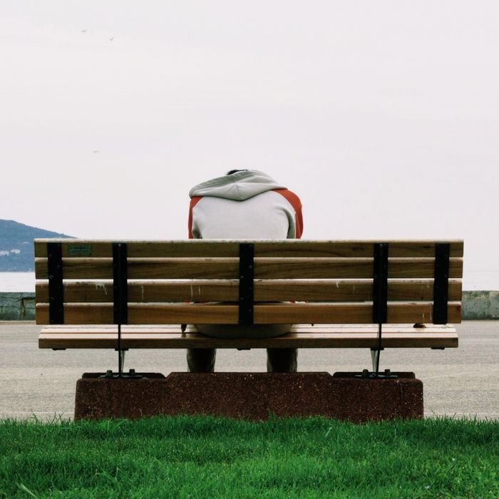 A person sitting alone on a bench, capturing solitude and contemplation by the riverside.