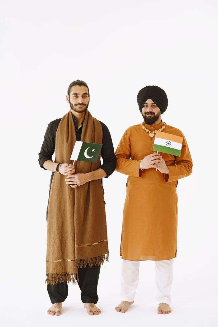 Two men standing with Indian and Pakistani flags on a white background symbolizing harmony.